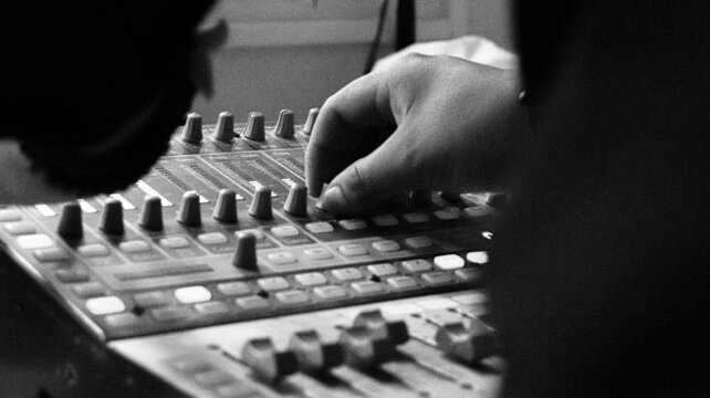 Mano ajustando controles de una consola de sonido