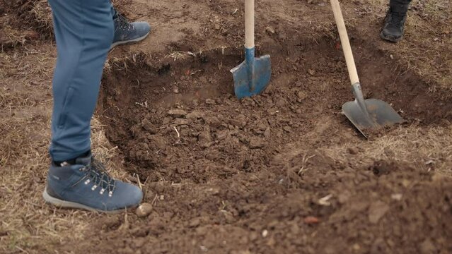 Archaeological site of world war ii mass grave. Digging pit. Pit in ground. Shovel. Dirty shovel in fresh soil. Deep hole in ground. Rusty old tool on construction. Dig deep ditches and pits.