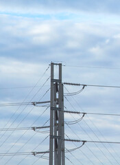 Medium voltage pylon with ceramic insulated wires to protect against electric shock and a large number of electric wires on a blue sky background in the evening.