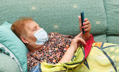 Older lady with mask looking at her smartphone