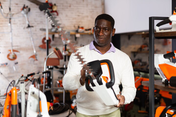 Adult serious man with an brush cutter in hardware store