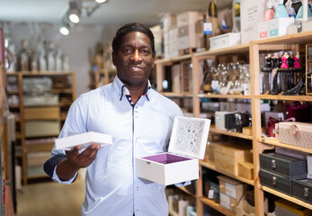 Obraz premium Portrait of adult African American choosing jewelry storage box at store of household goods