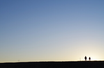Obraz na płótnie Canvas 夕陽と土手に立つ人のシルエット