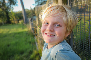 Blonde 10 year old boy relaxed and happy smiling on farm
