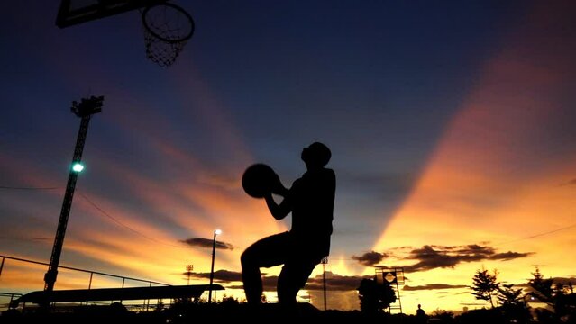 Silhouette of sport man dunk basketball slow motion