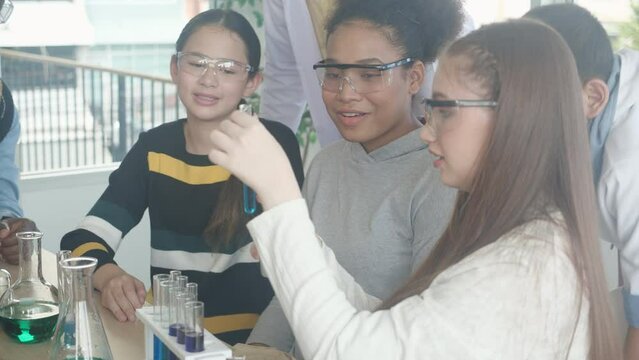 Young teacher teaching group student about science and explaining chemical for liquid in the lab of school, children studying and learning experiment science in the laboratory, education concept.