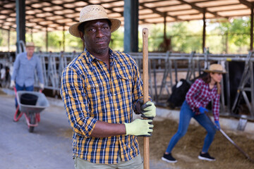 Portrait of confident young adult man farmer posing on dairy farm