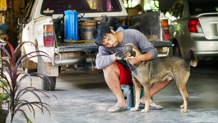 Fototapeta na wymiar The concept of dogs and humans. An Asian man sits with a dog in his home. Date 12 May 2022 Thailand