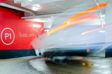 Commercial Parking Lot Level 1 Sign on Red Wall with White Car Driving Past with Motion Blur