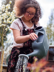 Girl watering plants in backyard