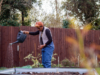 Woman watering plants in backyard © Cultura Creative
