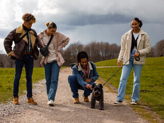 Fototapeta premium Group of young friends with dog in countryside