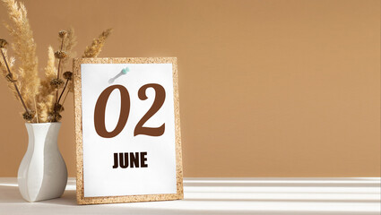 june 2. 2th day of month, calendar date.White vase with dead wood next to cork board with numbers. White-beige background with striped shadow. Concept of day of year, time planner, summer month