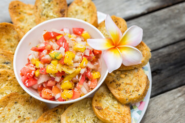 Closeup Homemade mango salsa with garlic bread with space on wooden table background, healthy snack
