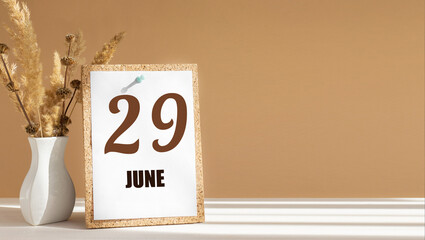 june 29. 29th day of month, calendar date.White vase with dead wood next to cork board with numbers. White-beige background with striped shadow. Concept of day of year, time planner, summer month