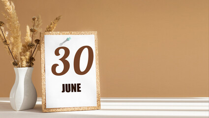 june 30. 30th day of month, calendar date.White vase with dead wood next to cork board with numbers. White-beige background with striped shadow. Concept of day of year, time planner, spring month