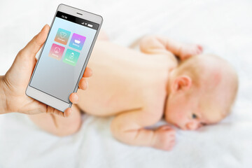 Woman using smartphone for remote baby care and distant control
