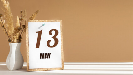 may 13. 13th day of month, calendar date.White vase with dead wood next to cork board with numbers....