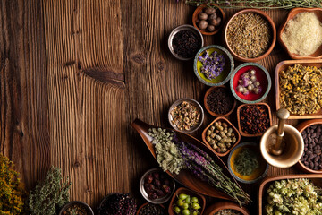 Natural medicine background. Assorted dry herbs in bowls and brass mortar on rustic wooden table.