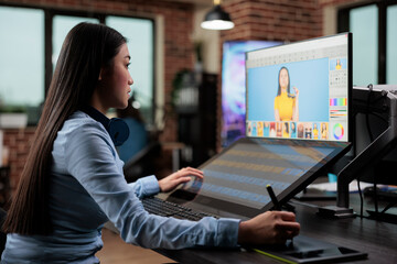 Creative agency asian employee retouching digital photos while using touchscreen display and stylus...