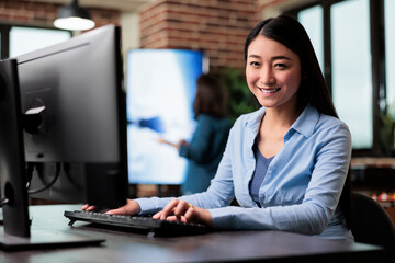 Creative department team leader developing digital art and professional 3D products while looking at camera. Smiling company employee sitting at desk in office workspace while looking at camera.