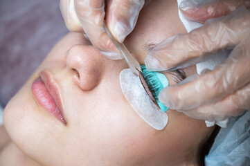 The master combs the eyelashes of a woman with a fish applicator. 