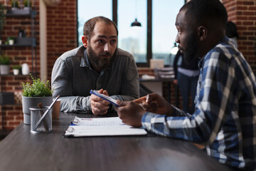 Executive manager interviewing confident man while reviewing CV and asking questions about work...