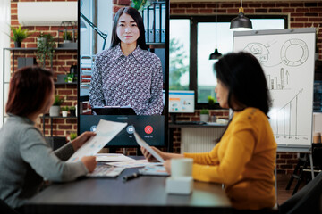 Businesswomen collaborating together at management project discussing business ideas during online videocall meeting conference in startup office. Teleconference call on monitor screen