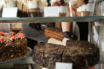 glass showcase of pastry shop with cakes, chocolate cake on display, take a piece of cake in cafe, bake shop