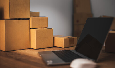 Cropped shot of portable office desk with mock-up computer devices, supplies and decorations on wood table. Mock up Copy Space Blank Screen Concept Business Working on Laptop. delivery paper boxes.