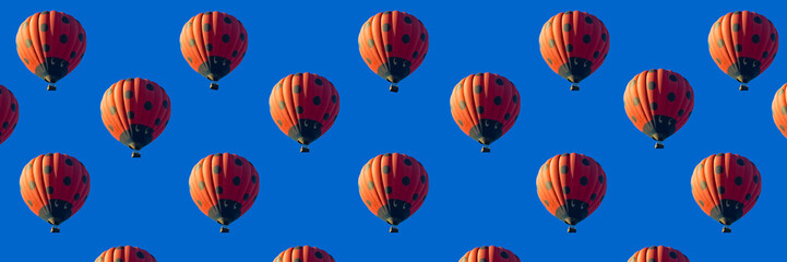 Red hot air balloon banner decorated as ladybird flying in clear blue sky