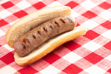 Grilled Bratwurst in a Bun on a Red and White Table