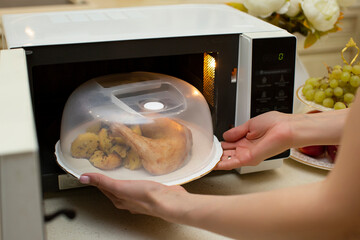 A plate of food in the microwave covered with a lid. The benefits and harms of microwave radiation...