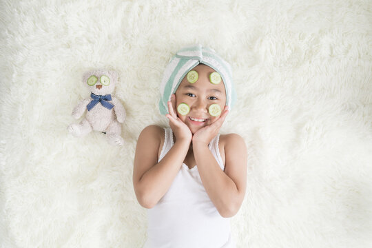 Top view Asian child little girl wear a turbine, towel and cucumber face mask.