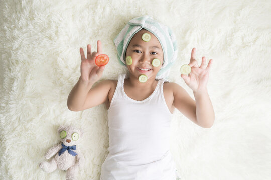 Top view Asian child little girl wear a turbine, towel and cucumber face mask.