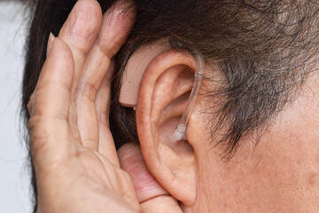 Electronic hearing aid device in the ear of Asian man with total deafness.