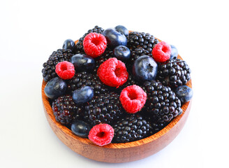 Fresh berries in a wooden plate over white background.
