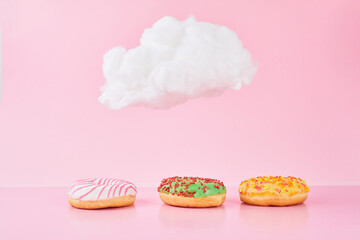 Sweet donuts with sprinkel and milk under a small cloud on a pink background. Various decorated doughnuts as concept of a fresh delicious Breakfast.