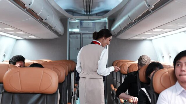 Asian beautiful female flight attendants checking safety of passenger before airplane take off and Group of people in airplane. Beautiful air hostess or fight attendant service passengers on board.