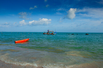 Blurred nature background of the morning sun by the sea, a beautiful golden light, among the trees, rocks and local fishing boats, the beauty of nature during the day.