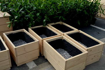 preparation for planting flower pots. wooden flower pots are filled at the bottom with gravel as drainage. the sides are covered with black foil with bubbles - Powered by Adobe