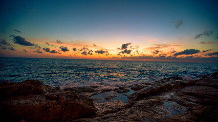 Blurred nature background of the morning sun by the sea, a beautiful golden light, among the trees, rocks and local fishing boats, the beauty of nature during the day.