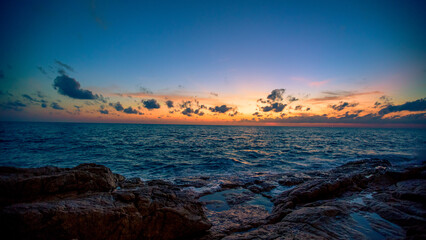 Blurred nature background of the morning sun by the sea, a beautiful golden light, among the trees, rocks and local fishing boats, the beauty of nature during the day.