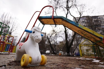 Empty playground in a residential area with colorful climbing frame and slide and white pony