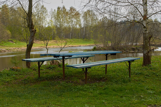 Wooden picnic table and two benches on the river bank