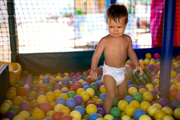 Fototapeta na wymiar Boy in diaper with ball playing in playroom on weekend