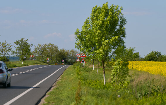 Roads photography. A straight road from Teleorman, Romania, is photographed between rapeseed agriculture fields. Transportation industry.