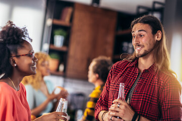 Beautiful young people in casual clothes are resting with bottles of drink, talking and smiling