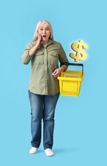 Shocked mature woman with empty shopping basket on blue background. Price increase