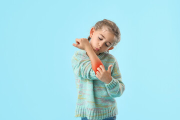 Little girl with allergy scratching herself on light blue background